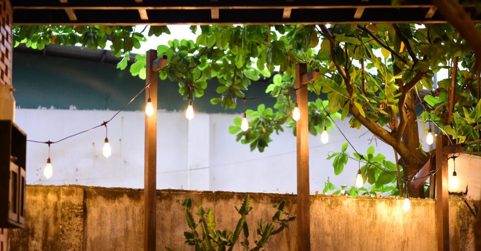 Backyard patio glowing with warm string lights and lanterns set up for evening entertaining
