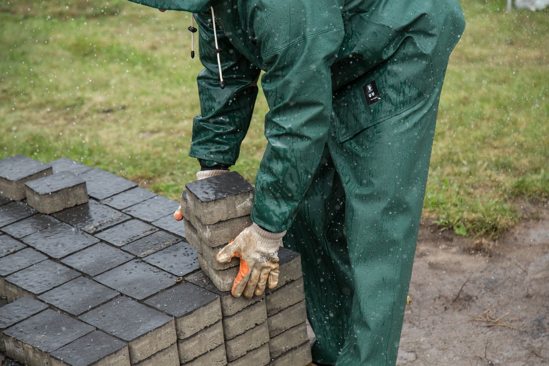 Worker placing paving stones during patio construction