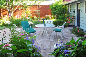 Brick paver patio framed by dense flower beds and mixed planting