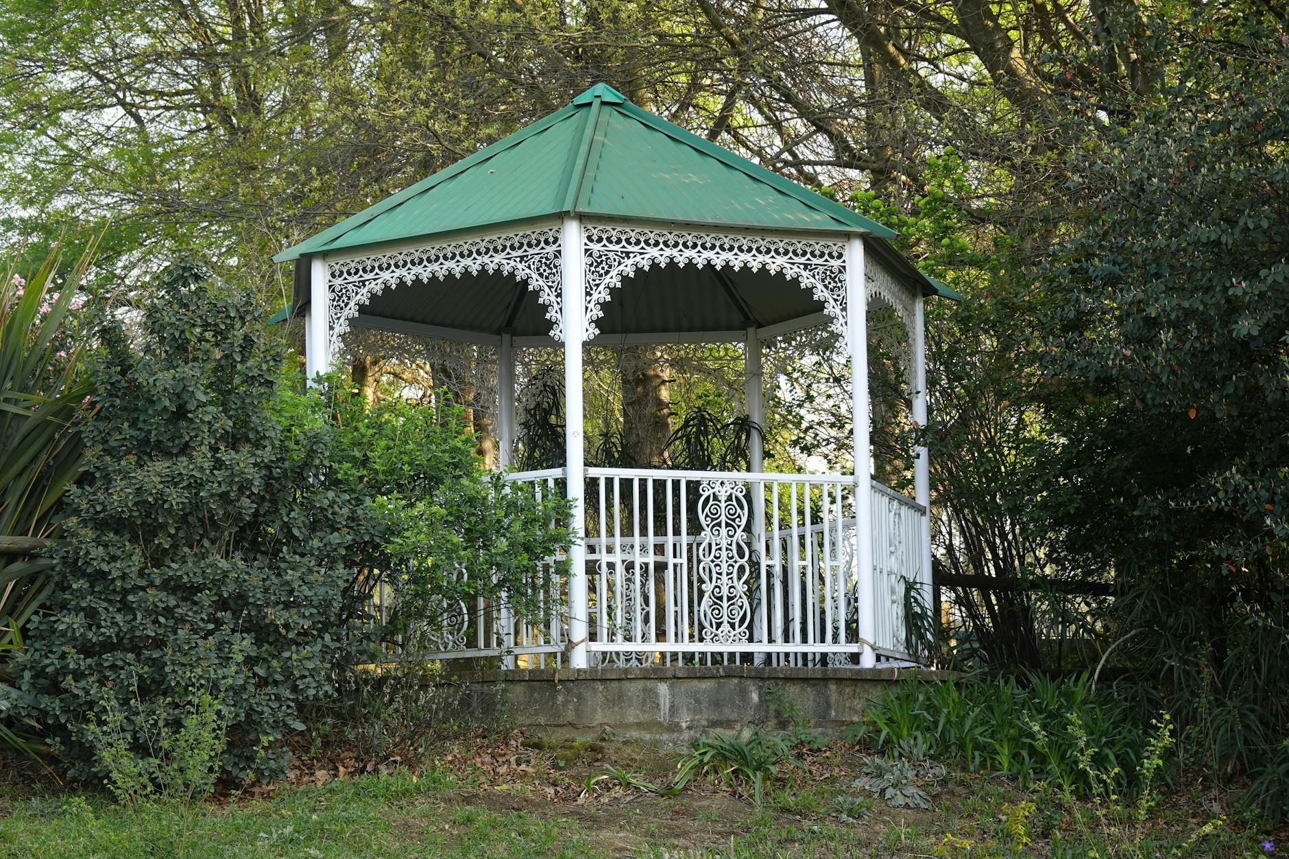 Classic white gazebo surrounded by lush greenery in a private garden