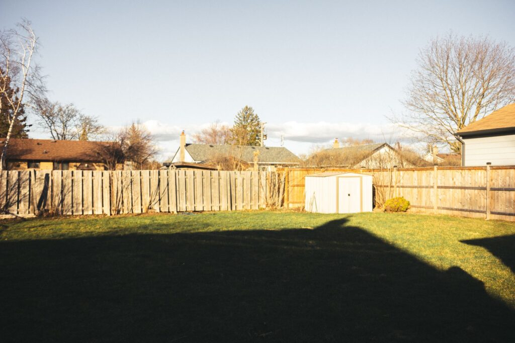 Bare residential backyard with a wooden fence and lawn before a new patio is built