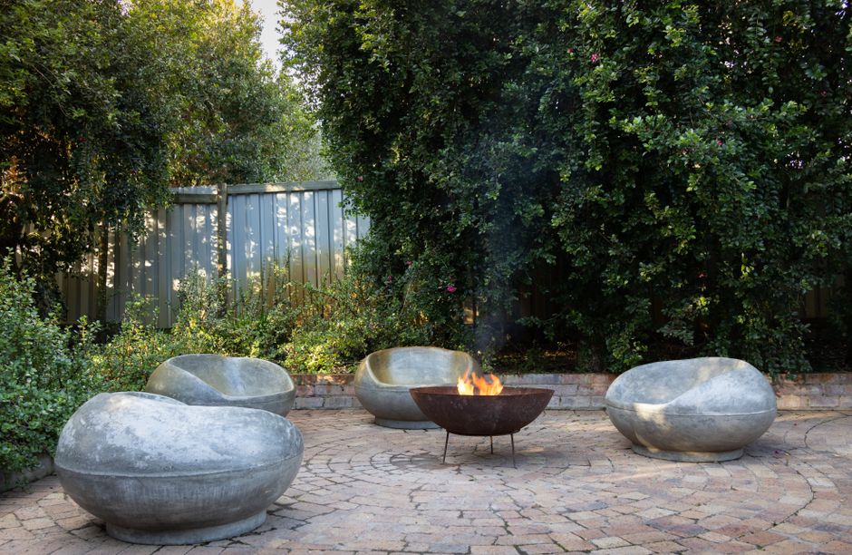 Content image 1  - Close-up of a stone fire pit surrounded by lounge chairs