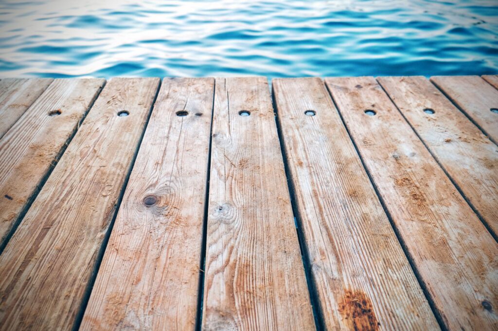 Hardwood deck planks beside open water, exposed to constant moisture