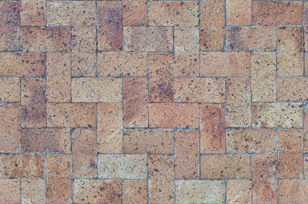 Brick pavers laid in a herringbone pattern showing colour and texture variation