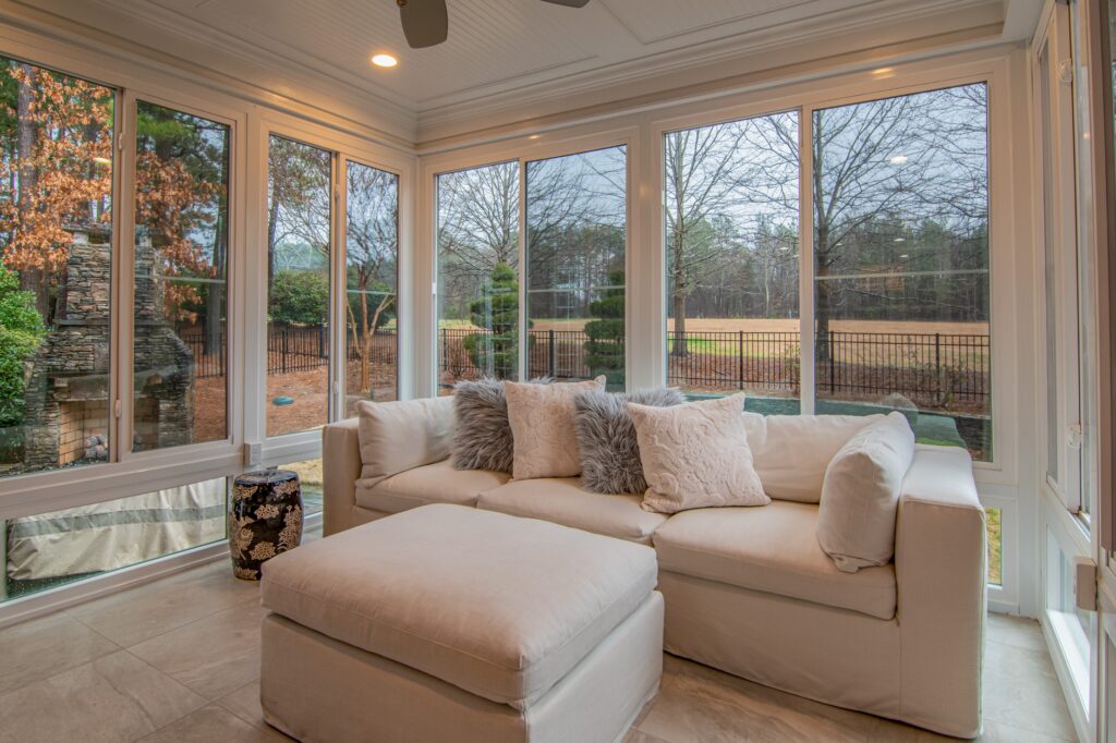 Sunroom furnished with a sofa and framed by large glazed windows on three sides