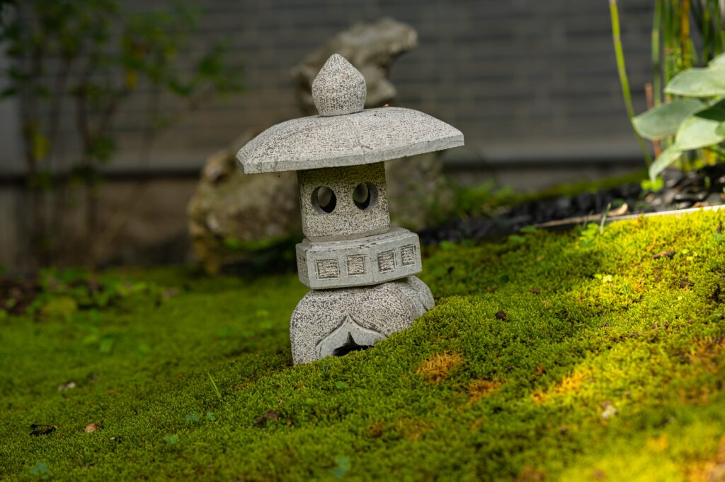 Stone lantern set on a bed of lush green moss in a Japanese-style garden
